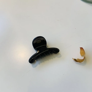Vue détaillée de dessus d'une pince à cheveux noire brillante avec ressort en métal doré