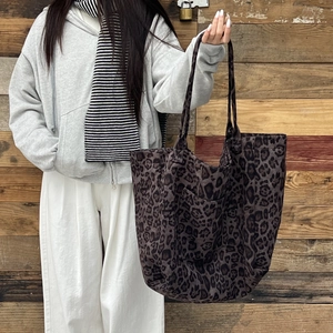 Detail of vintage leopard print tote bag with long shoulder straps on a wood background