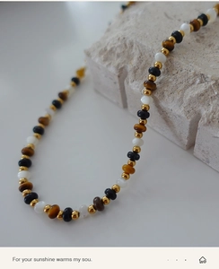 Macro shot of tiger eye beads and golden spacers on a textured stone display