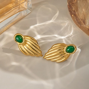Elegante goldene Ohrringe mit grünem Achat und flügelförmiger Textur auf hellem Grund