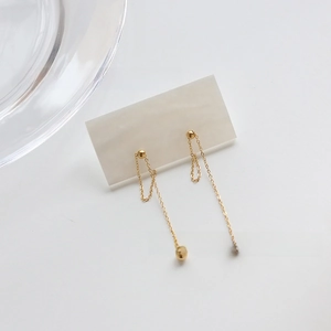 Detailed view of elegant gold tassel earrings with metal bead and delicate chain