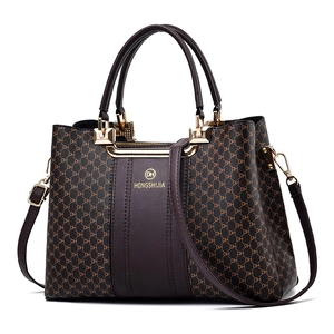 Brown vintage tote bag with DH pattern print and golden hardware on white background
