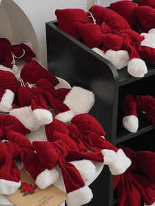 Detail view of red velvet Christmas bows with white pom-poms on a display shelf