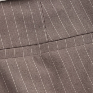 Close-up of brown pinstripe fabric texture and professional stitching on dress trousers