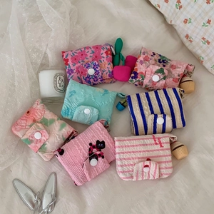 Close-up of cute floral cotton coin purses with snap buttons and cupcake charms on a bed