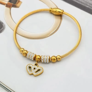 Détail d'un bracelet câble torsadé doré avec doubles breloques cœurs en zircon