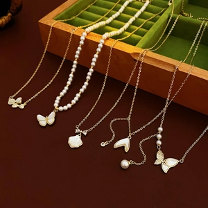 Aperçu de cinq colliers dorés avec pendentifs perle et papillon dans un coffret en bois