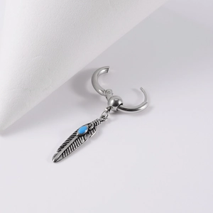 Detail of silver feather earring with blue turquoise stone inlay on a polished steel hoop