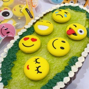Macro shot of yellow emoji face erasers with various expressions on green texture