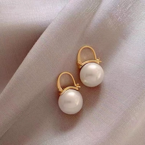 Elegant gold-plated pearl drop earrings displayed on a soft purple silk fabric background
