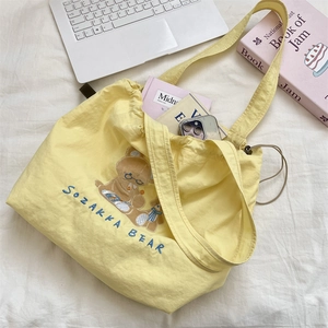 Detail of yellow canvas tote bag with cute bear embroidery and drawstring closure