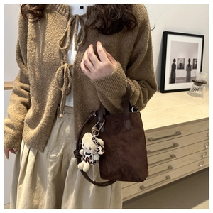 Detail of dark brown suede crossbody bag styled with a brown knit cardigan and beige skirt