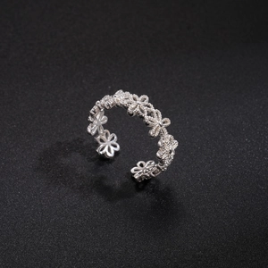Detail shot of silver hollow floral pattern on adjustable open ring with metallic texture