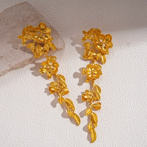 Détails d'oreilles pendantes fleurs métalliques dorées avec pétales à texture fine