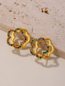 Macro detail of 18K gold plated flower earring with colorful zircons on stone surface