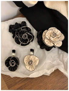Close-up of elegant camellia hair scrunchies and pearl clips in black and cream satin