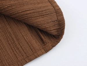 Macro detail of dark brown ribbed knit fabric with professional double-stitched hem