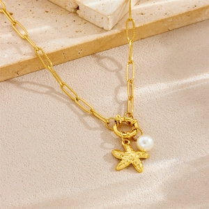 Gold starfish pearl necklace with link chain on neutral textured stone background