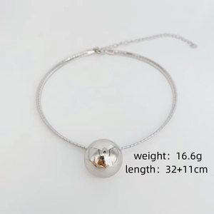 Minimalist silver collar necklace with sleek metal ball pendant on white background