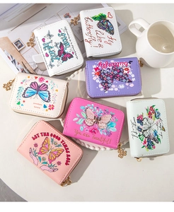 Close-up of butterfly embossed PU leather wallets with clover zipper charms on a desk