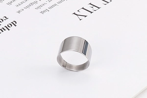 Macro top view of a wide silver stainless steel band ring on a minimalist background