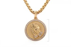 Macro detail of 18K gold plated hip hop pendant with praying hands and cubic zirconia