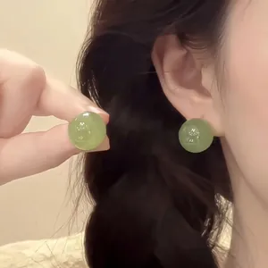 Detailed view of light green round crystal bead earrings on model with gold plating