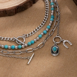 Macro detail of layered beaded necklace with horseshoe pendant and turquoise stones