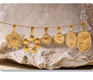 Detail of 18K gold-plated geometric pendants on thin chains over natural rock background