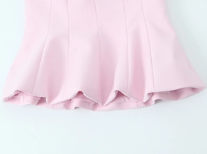 Detail of pink tube top featuring a ruffled peplum hem and smooth fabric texture
