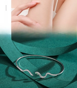 Detailed view of s925 silver snake bangle with sparkling zircons and green gemstone eye