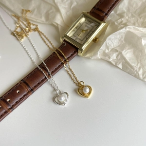Detail of gold and silver heart pearl necklaces on elegant leather and paper background