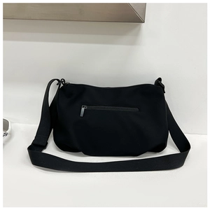 Detail view of the black crossbody bag showing back zipper pocket and nylon material