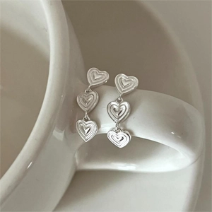 Elegant S925 sterling silver triple heart drop earrings on a ceramic cup handle
