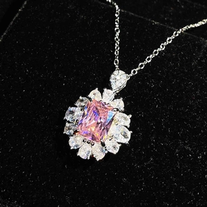 Macro detail of a silver pendant with a pink emerald-cut gem and teardrop stones