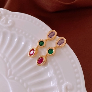 Detail of vintage drop earrings with purple, green, and red gemstones in gold frames