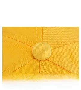 Dettaglio della parte superiore del berretto giallo con bottone e cuciture rifinite