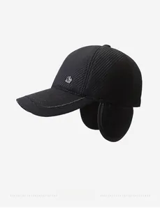 Detailed side view of black winter baseball cap with ear flaps and metal badge