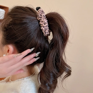 Detail of leopard print fabric scrunchie with soft pleats on a ponytail hairstyle