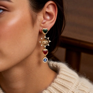 Close-up of bohemian tassel earrings with heart gems and evil eye charm on a model