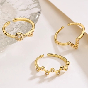 Three gold minimalist open rings with zircon stones in round, V-shape and wavy designs