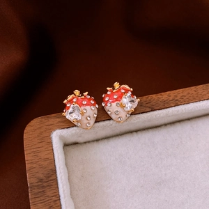 Détail de boucles d'oreilles fraise en émail rouge avec zircon en forme de cœur