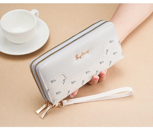 Close-up of white quilted long wallet with double zippers and golden hardware details