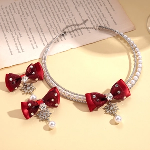 Close-up of pearl necklace with red ribbon bow and rhinestone snowflake pendant