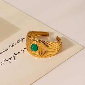 Detail of a vintage gold-plated textured ring with a green gemstone inlay on a card