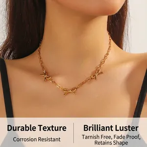 Close-up of golden bow chain necklace with three hollow bow charms on a model