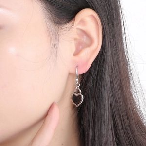 Close-up of black heart-shaped drop earrings in silver finish worn by a model