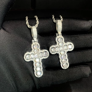 Two hip-hop style silver cross pendants with shimmering cubic zirconia on black background