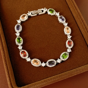 Detailed close-up of oval multi-color gemstones and white zircon set on a silver bracelet