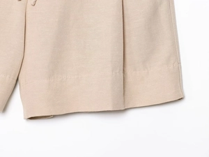 Close-up of beige linen blend fabric showing double stitching and hem detail on shorts